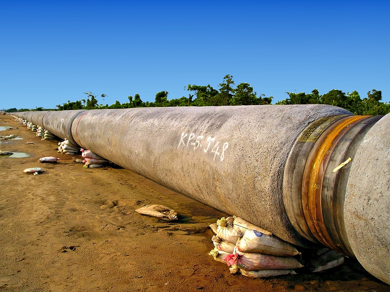 Concrete-coated pipe string on sandbag supports