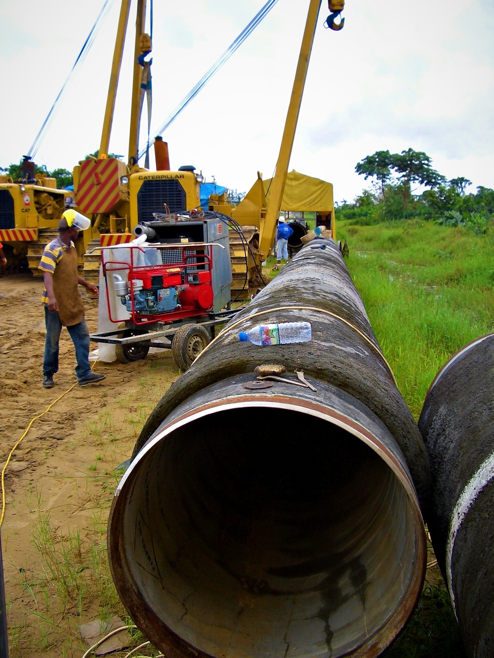 Pipe ends lined up on the right-of-way with sidebooms behind