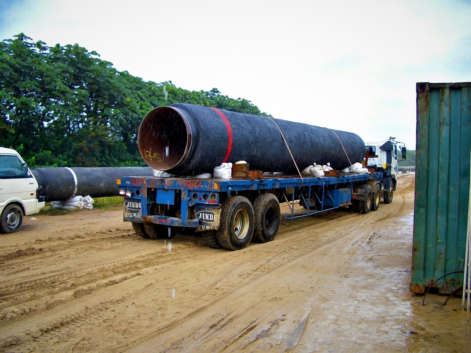 Coated line pipe joint on a flatbed trailer hauled along the right-of-way