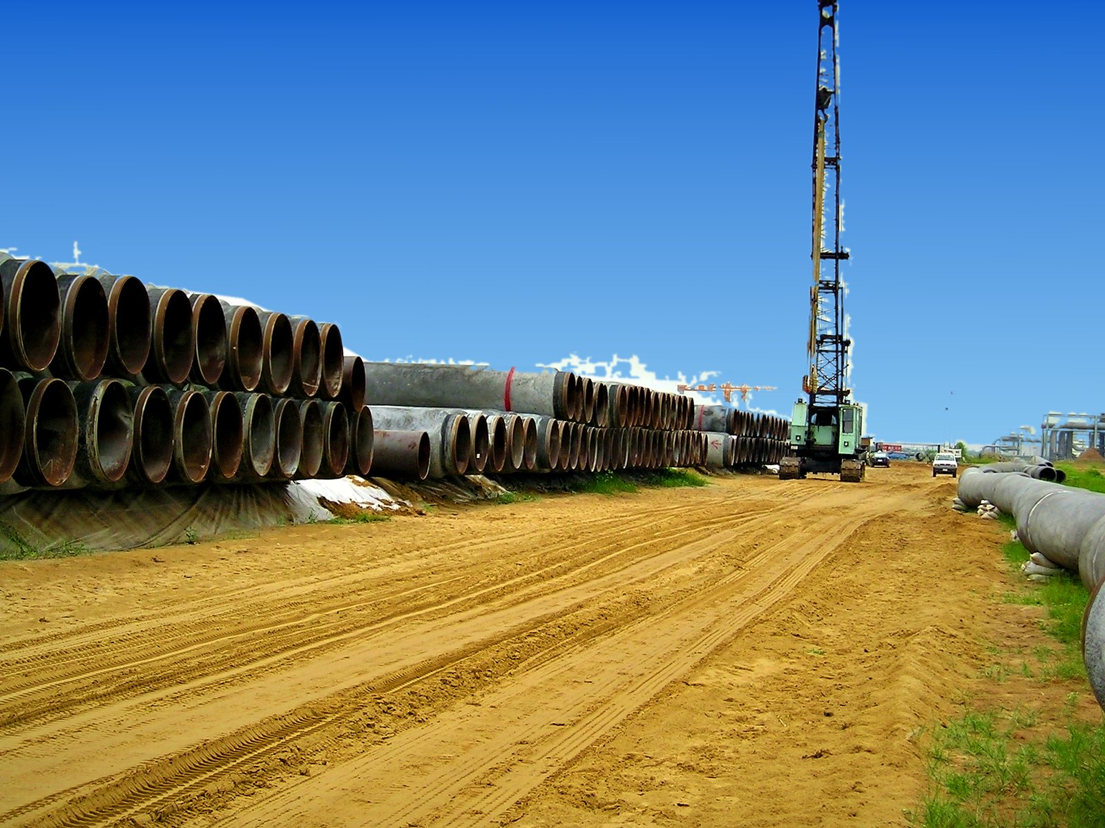 Line pipe stockpiled in the pipe yard with a crawler crane for handling
