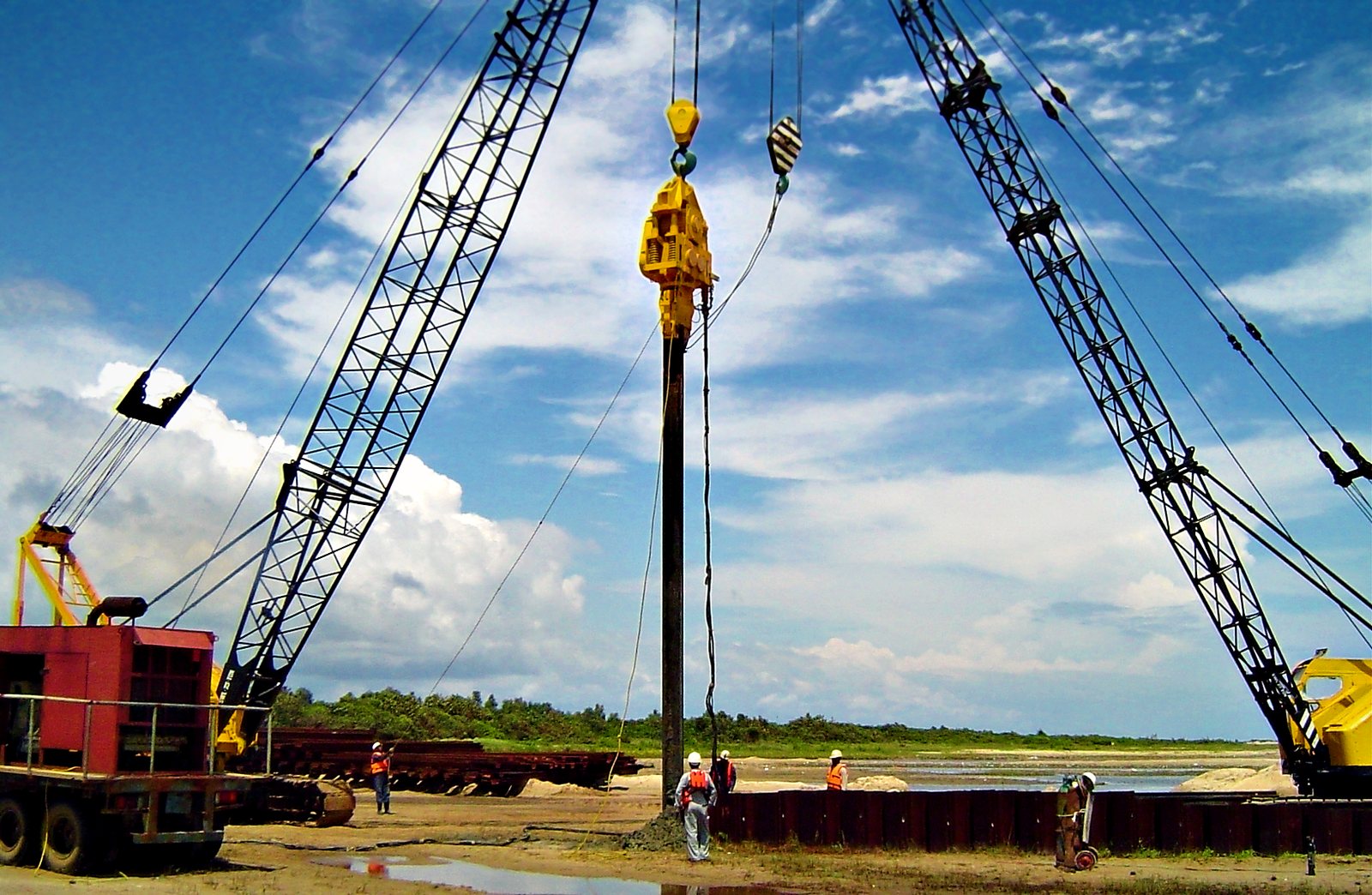 Two crawler cranes driving cofferdam sheet piles with a vibro hammer