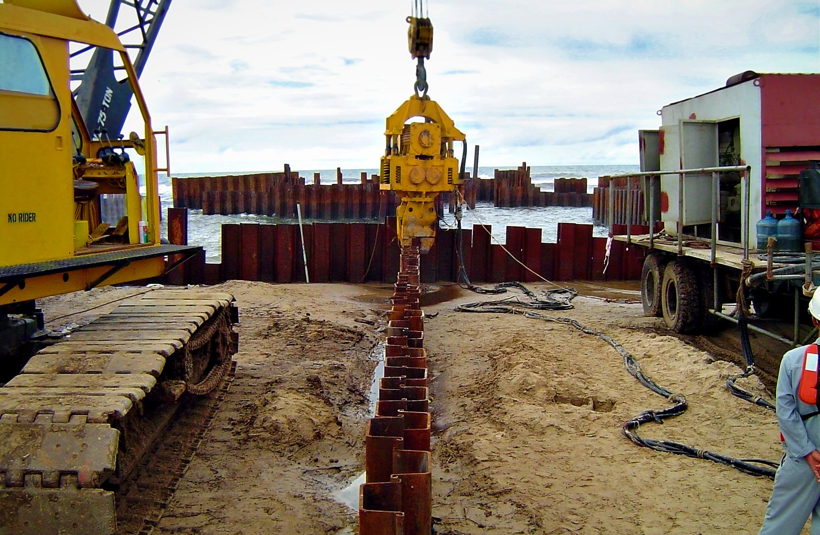Vibro hammer installing a line of sheet piles toward the sea