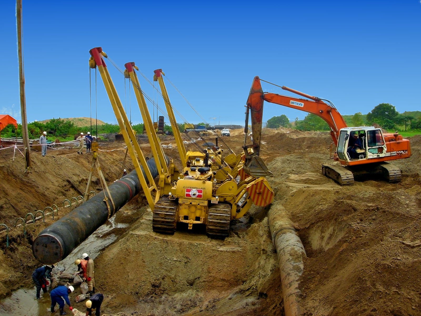 Sideboom and excavator working at an open trench