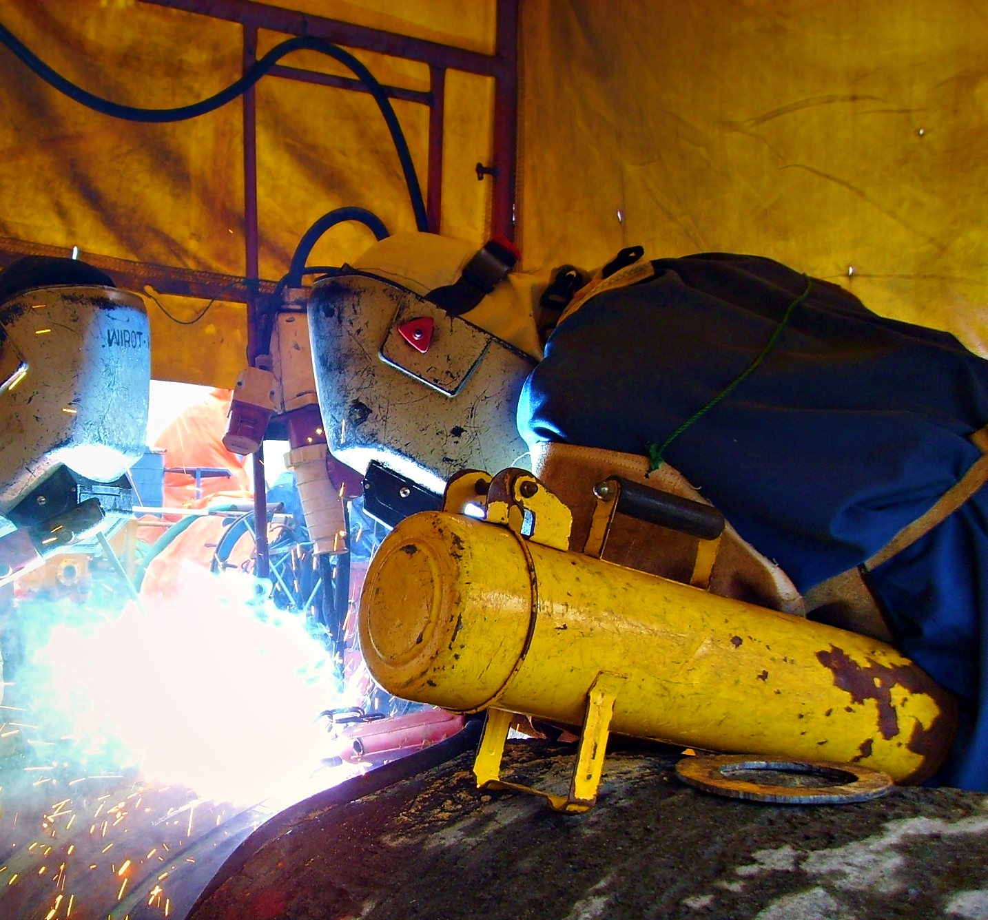 Welder at work on a pipeline joint inside a welding shelter